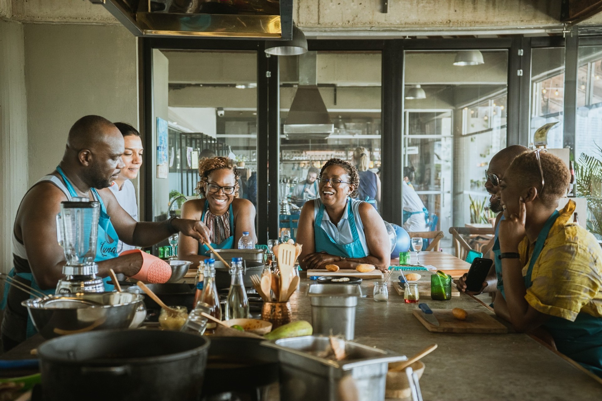 Small group of guests laughing and cooking together during a hands-on Colombian cooking class at Lunático