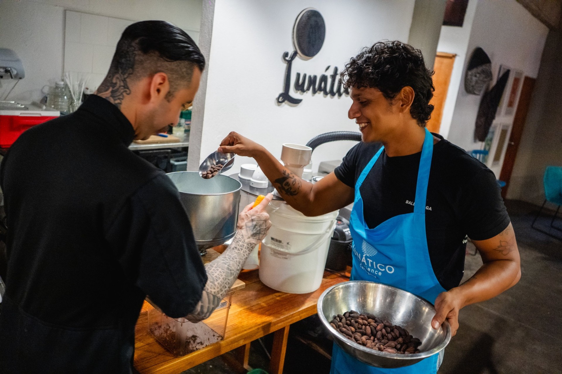 Host and guest interacting with cacao beans and origin materials at Lunático in Cartagena